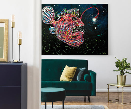 A colorful abstract painting of a bioluminescent anglerfish on a black background, displayed on a white wall in a modern living room setting above a teal velvet sofa.