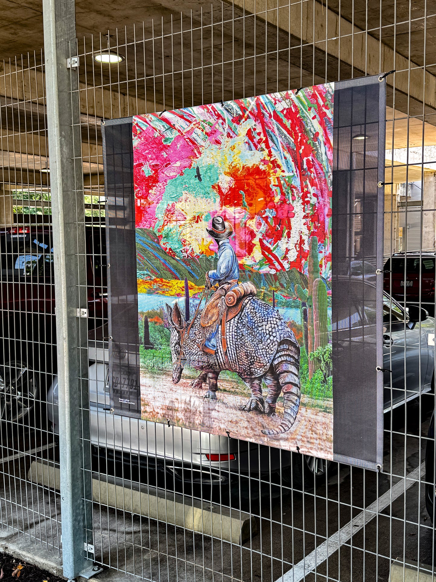 Colorful artwork of a cowboy riding a giant armadillo with a vibrant abstract sunset background. Armadillo Cowboy Sunset by Doug LaRue mural installed in downtown Round Rock Texas