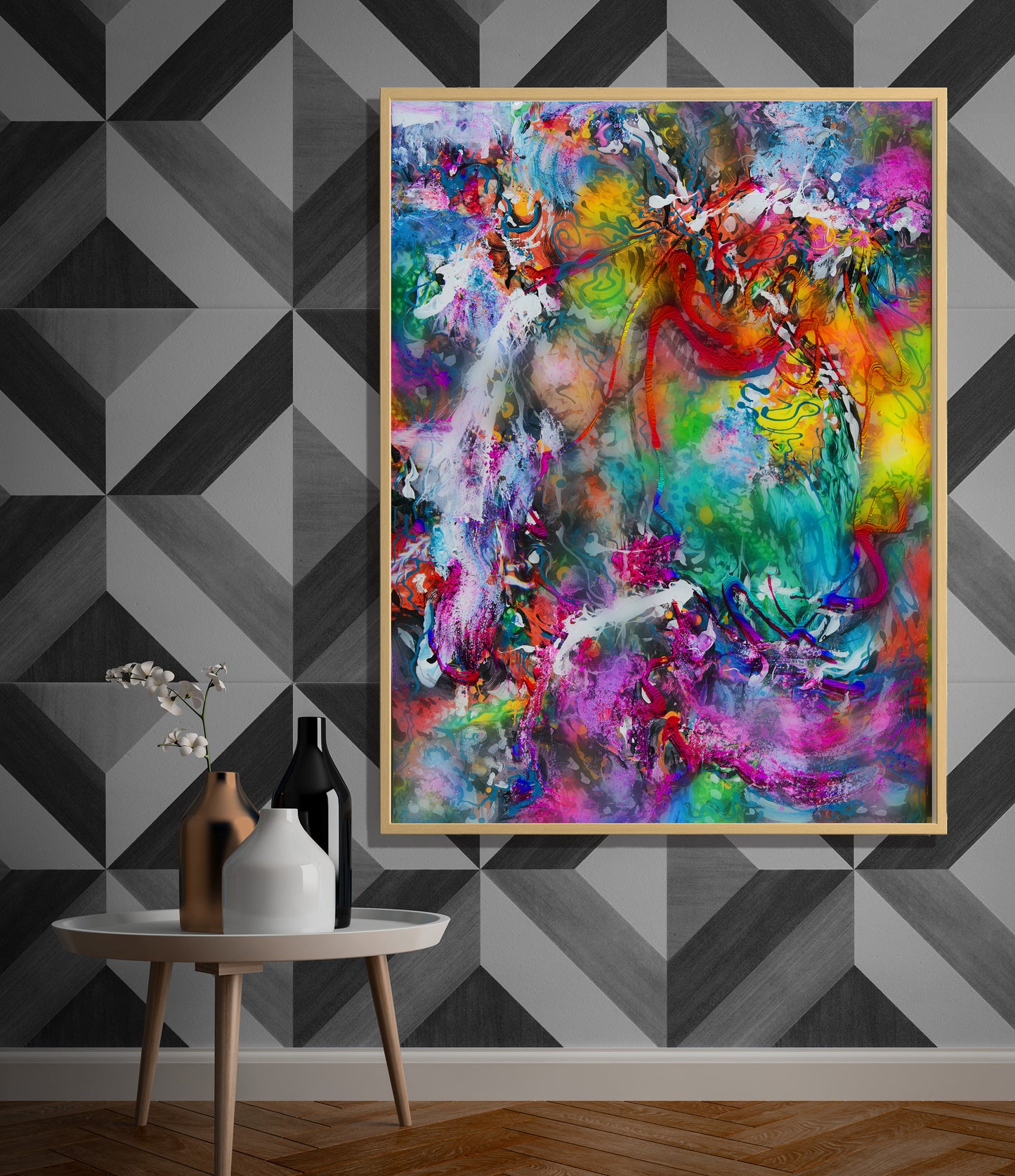 A large framed abstract canvas print with vibrant multicolor brushstrokes hangs on a geometric gray wallpapered wall above a small round side table with decorative vases. Balcones Pop Tart by Doug LaRue