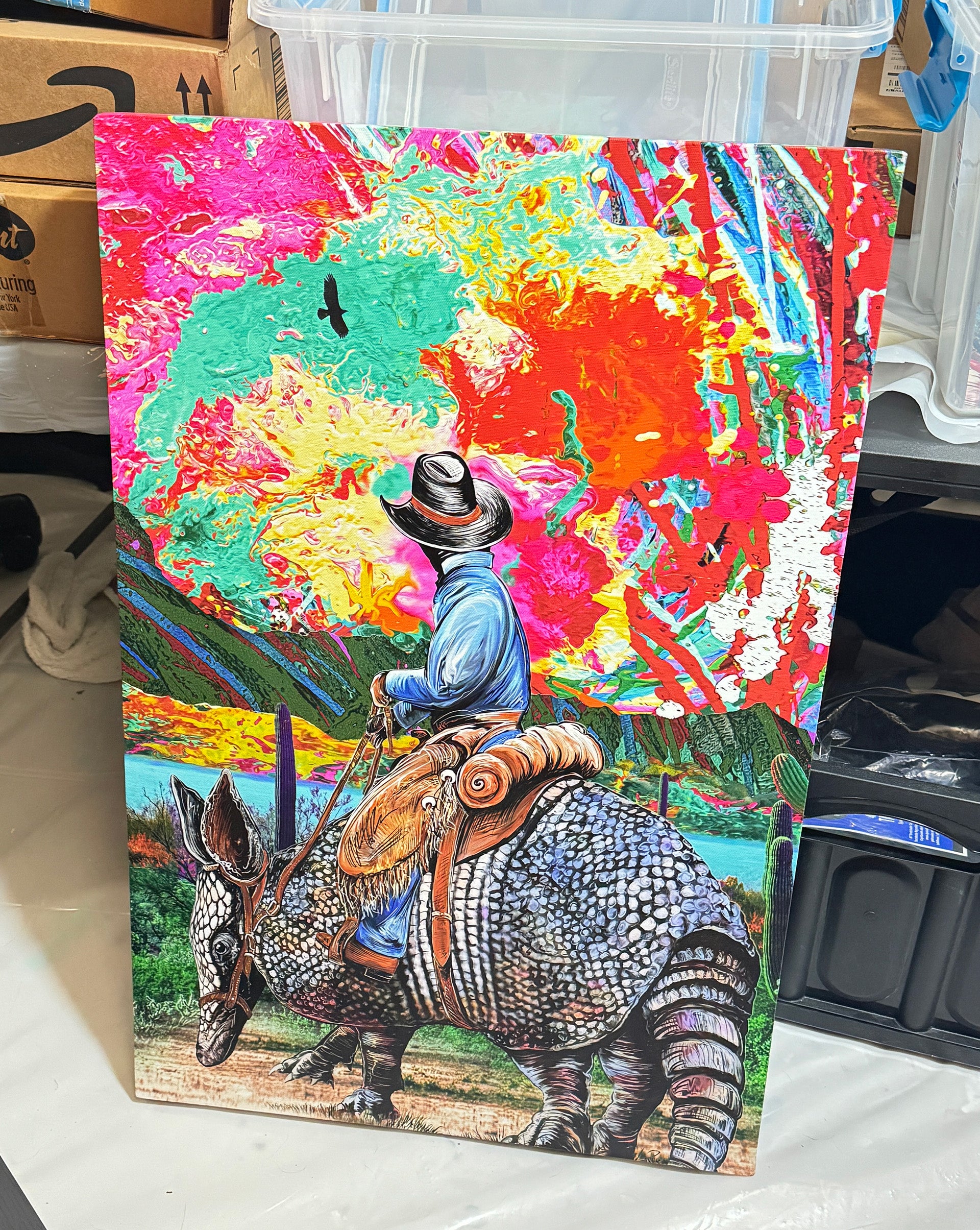 Colorful artwork of a cowboy riding a giant armadillo with a vibrant abstract sunset background. Armadillo Cowboy Sunset by Doug LaRue 20x30x1.5 in. mixed media canvas.