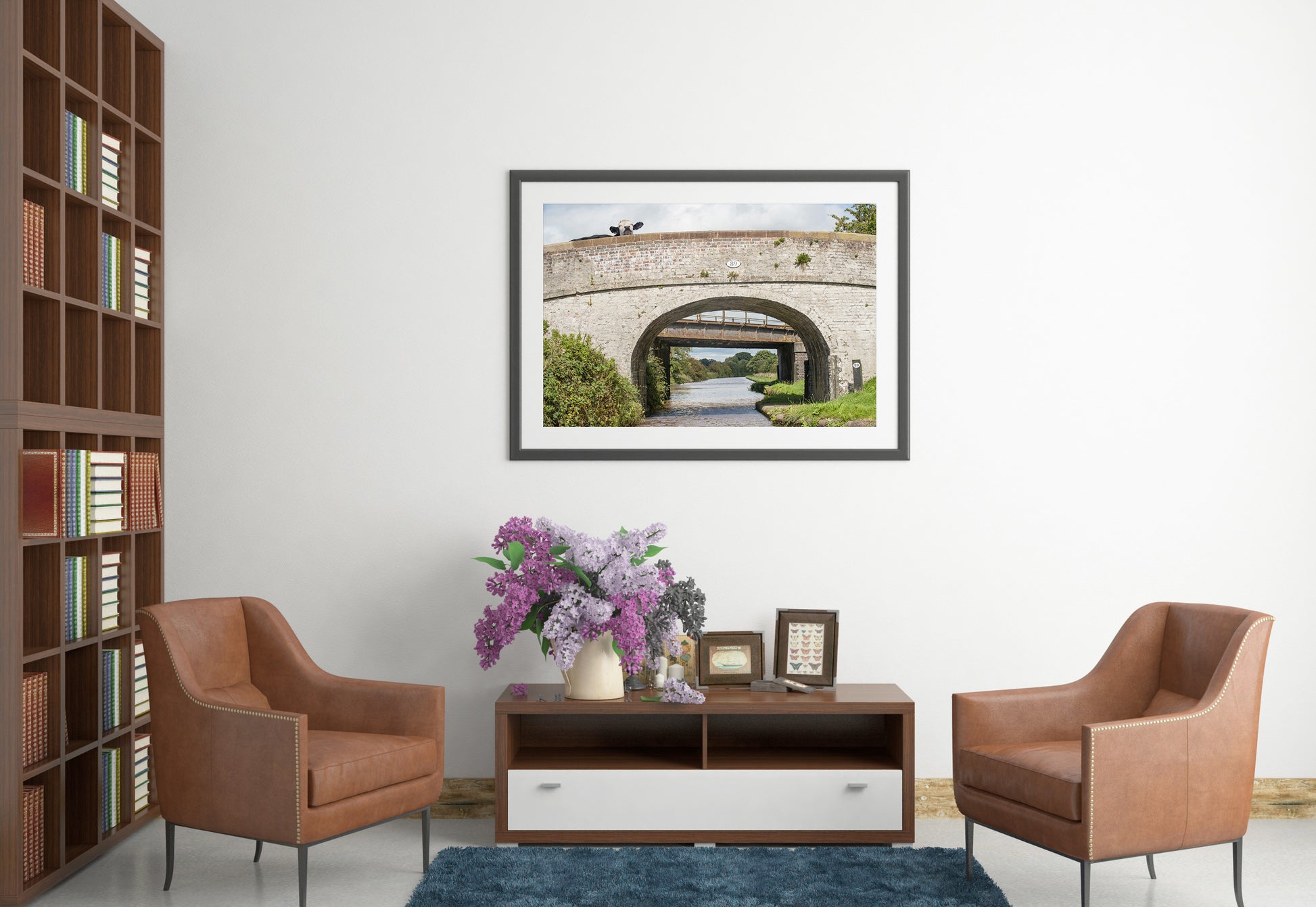 Living room with brown chairs, a coffee table with a vase of flowers, and a framed picture of a bridge on the wall. Cow Bridge 89 photograph by Laura Rojo