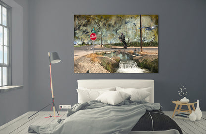 A canvas wall art print depicting a rustic watermill and stream scene with a stop sign, displayed on a dark gray wall above a neatly made bed in a modern bedroom setting. LaRue Road bye Doug LaRue