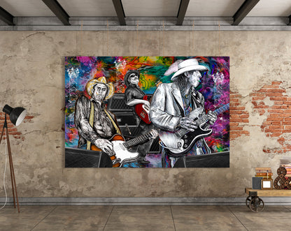 A large rectangular wall art print showing three illustrated guitarists in black-and-white with vivid multicolor paint splashes behind them, displayed on a textured beige wall in an industrial room with exposed brick and a floor lamp. Slim, Red and Stevie Ray by Doug LaRue