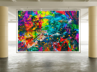 A large framed abstract wall art print hangs in a modern gallery space with two beige columns and a gray concrete floor. The artwork features a highly vibrant, multicolored abstract composition with splashes and drips of blue, green, yellow, pink, red, and orange. Bee Caves abstract mixed media by Doug LaRue