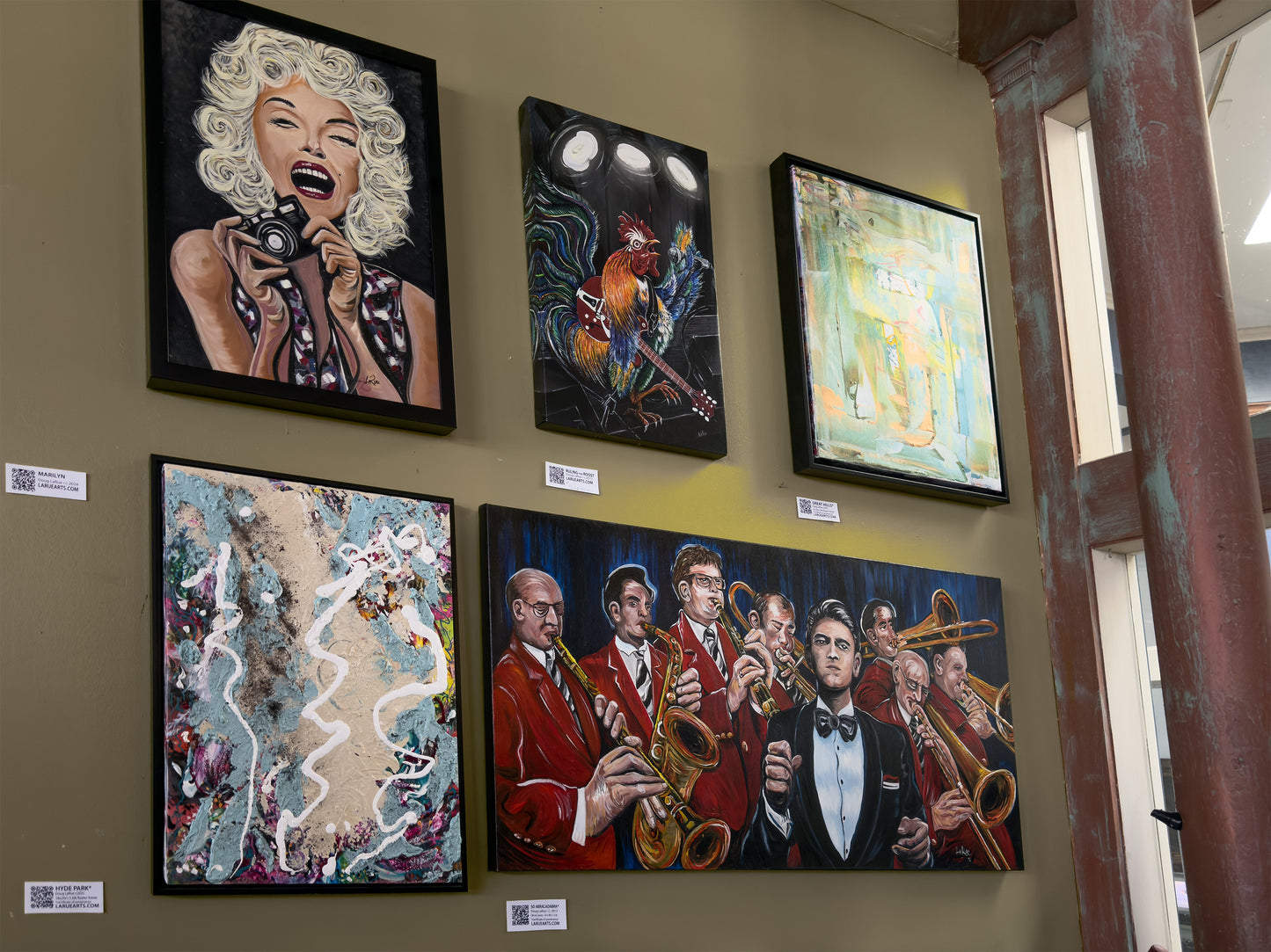 Artistic wall displays featuring various artworks on a muted yellow wall.