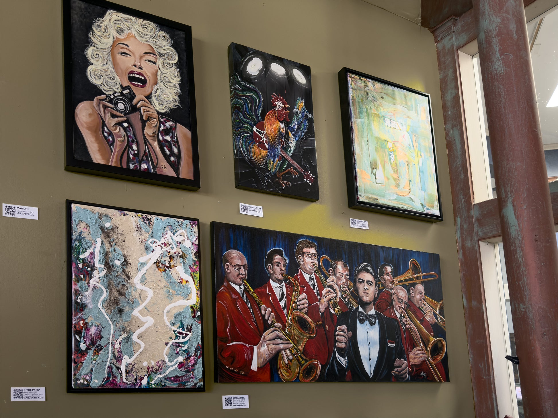 Artistic wall displays featuring various artworks on a muted yellow wall.