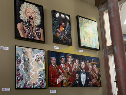 Artistic wall displays featuring various artworks on a muted yellow wall.