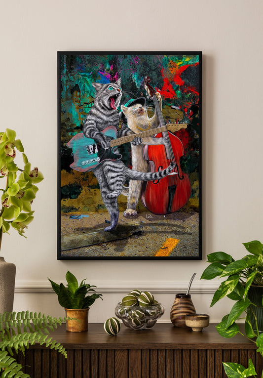 A framed colorful art print depicting two anthropomorphic cats playing music, hanging on a beige wall above a wooden console table with potted plants and decorative items.