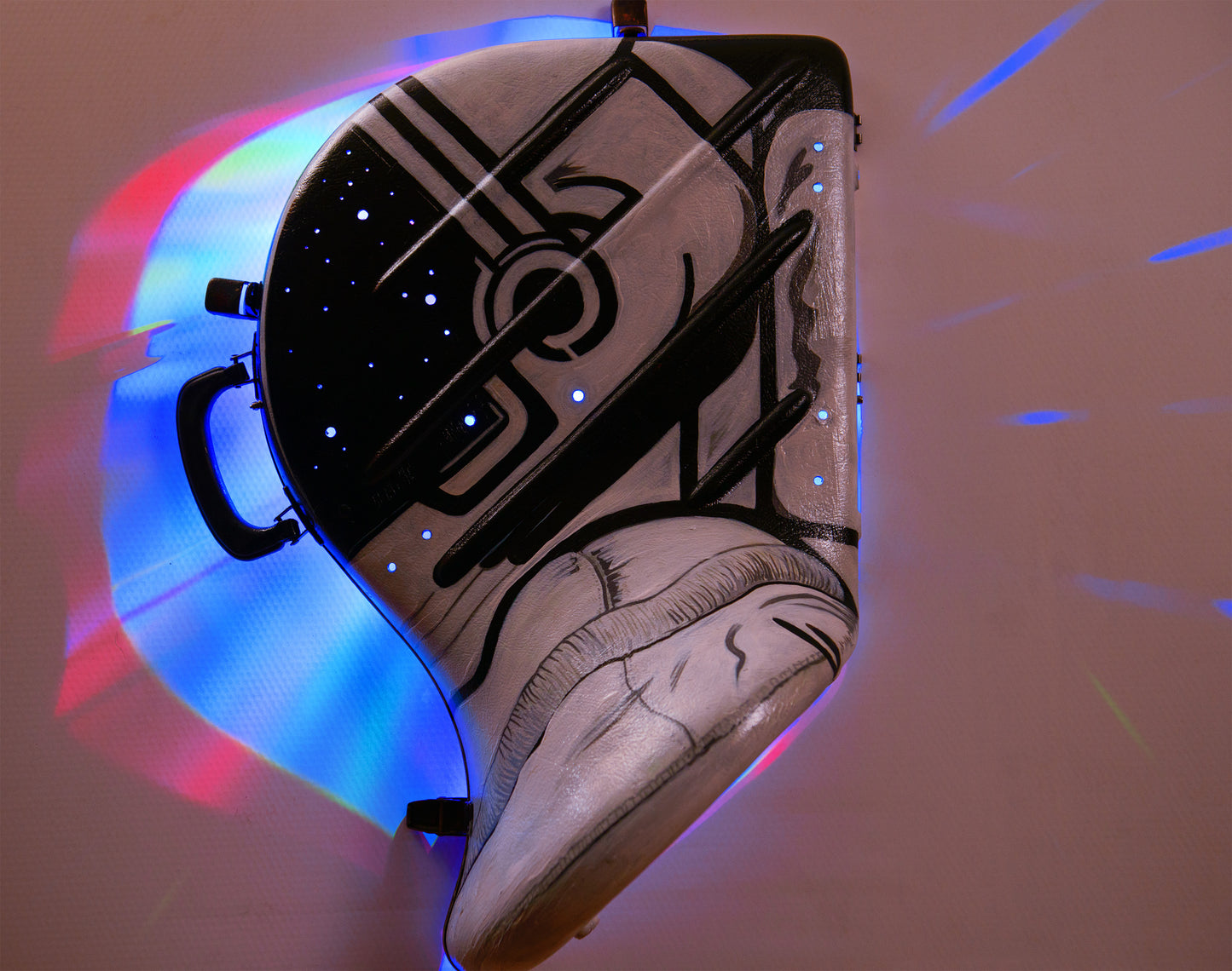 A hand-painted French horn case in the form of an astronauts helmet. Space Helmet with glowing LED party lights mounted inside to glow through hols in the helmet screen