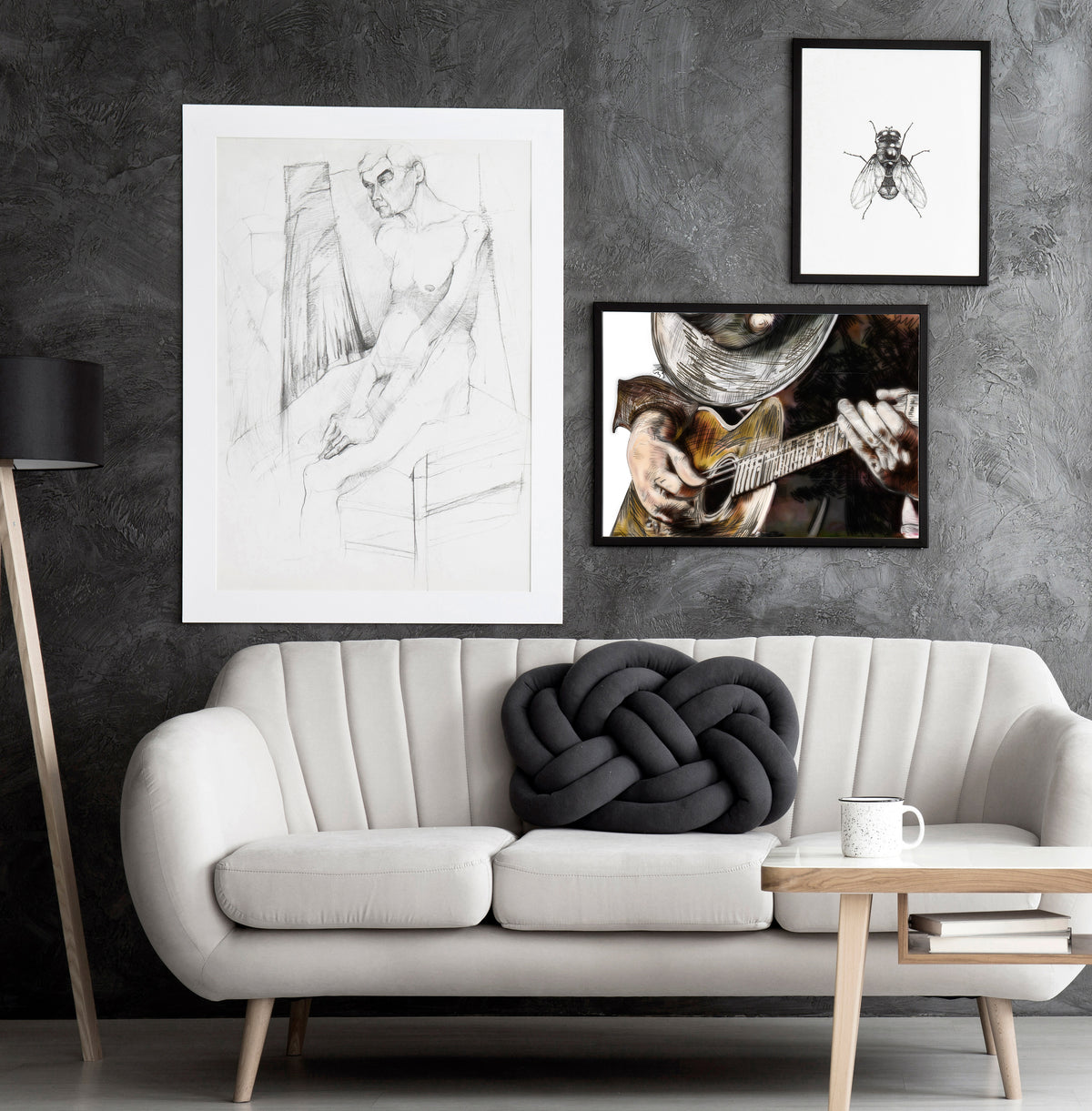 Three framed artworks on a textured grey wall over a modern white couch. SRV Sketch b y Doug LaRue