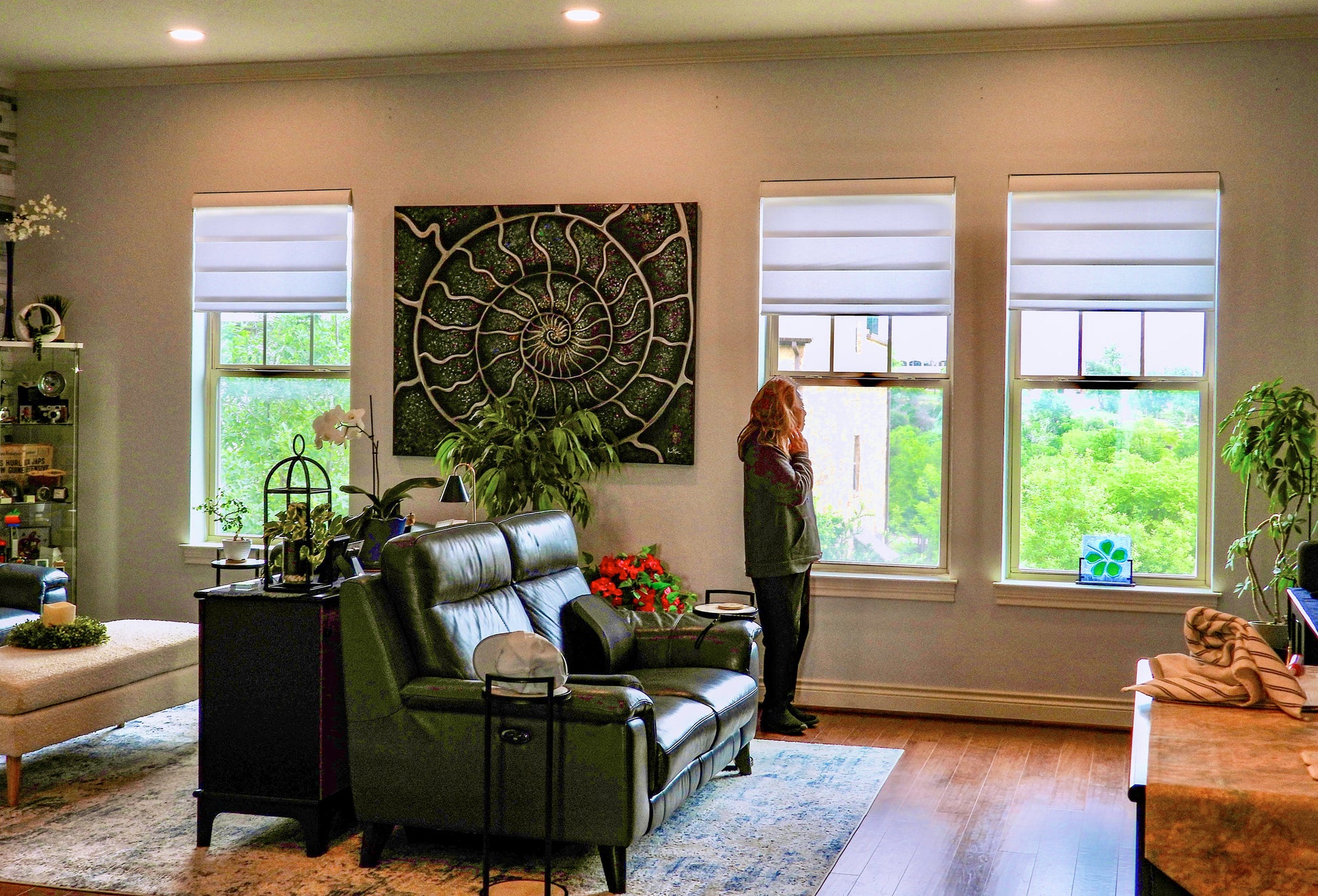 Living room with green sofa, decorative wall art, and large windows. Silver Blue Ammonite by Doug LaRue