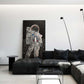 Astronaut standing on the moon observing a black hole framed print behind black leather couch